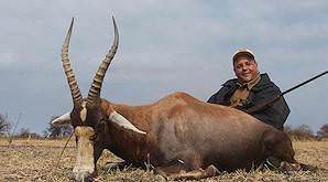 A huntress poses with her bontebok and professional hunter.