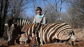A young hunter sit proudly behind his Burchell's zebra trophy.