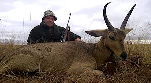 A hunter sits alongside his common reedbuck trophy.