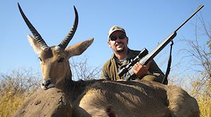 A hunter sits behind his common reebuck trophy.