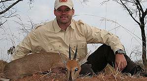 A hunter presents his grey duiker trophy for a photograph.