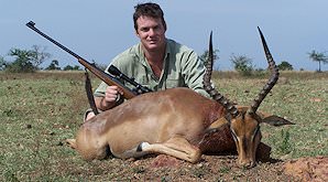 A hunter poses with his rifle and his impala trophy.