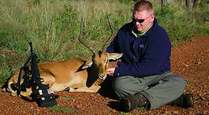 A hunter sits down alongside his impala trophy.