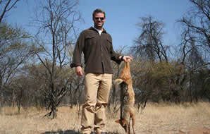 A jackal is held aloft for a hunting photograph.