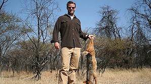 A hunter holds up his black-backed jackal for a photograph.