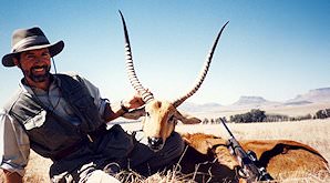 A hunter smiles proudly alongside his red lechwe trophy.