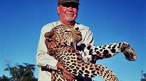 A hunter smiles with his leopard trophy.