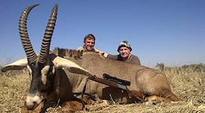 A hunter sits proudly alongside his roan antelope trophy.