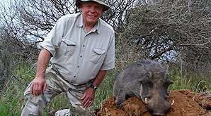 A hunter smiles alongside his warthog trophy.