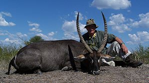 A hunter sits down behind his waterbuck trophy.