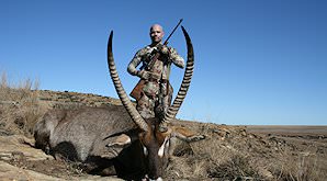 A huner stands behind his waterbuck trophy.
