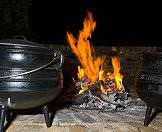 A potjie next to a fire at a rest camp.