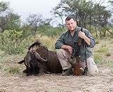 A hunter poses with a black wildebeest.