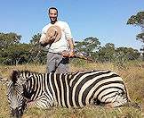 A hunter smiles with his zebra trophy.