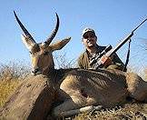 A hunter presents his common reedbuck trophy for a photograph.