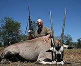 A hunter sits proudly alongside his gemsbok trophy.