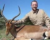A hunter happily shows off his impala trophy for a photograph.