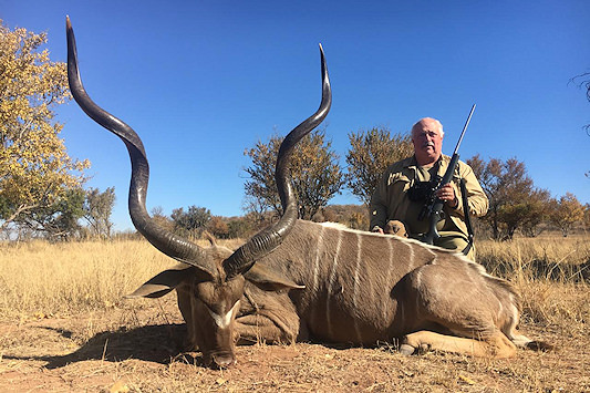 A hunter posing for a photo with a kudu trophy.