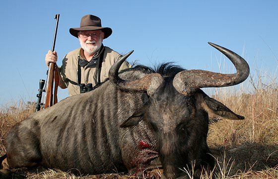 A hunter sits alongside his blue wildebeest trophy.