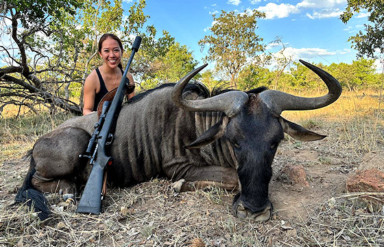 A hunter sits alongside his blue wildebeest trophy.