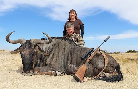 A hunter and his partner pose alongside a blue wildebeest trophy.