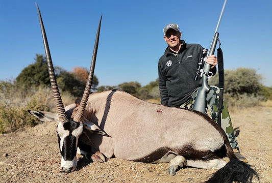 A gemsbok trophy is presented for a commemorative photograph.