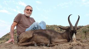 A hunter sits with his black springbok trophy.