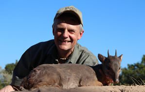 A hunter smiles with his blue duiker trophy.