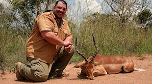 A hunter smiles alongside his impala trophy.