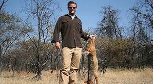 A hunter holds up a black-backed jackal for a photo.