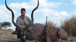 A hunter sits alongside his impressive kudu trophy.