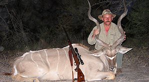 A hunter poses between the horns of his kudu trophy.