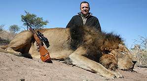 A hunter sits behind his lion trophy.