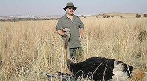 A ostrich is held up for a celebratory hunting photograph.