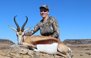 A huntress smiles with her springbok trophy.