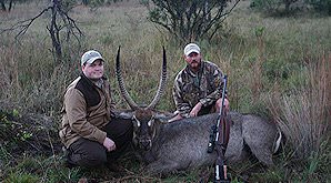 Two hunters sit alongside their waterbuck trophy.