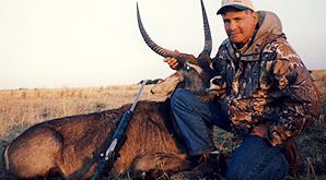 A hunter props up the head of his waterbuck trophy on his knee.