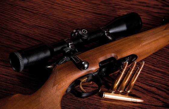 A close-up of a rifle, scope and bullets.