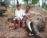 A  father and son with an elephant trophy.