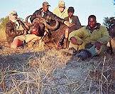 A hunter and his team pose with a Cape buffalo trophy.