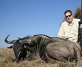 A hunter smiles alongside his blue wildebeest trophy.