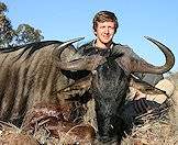 A hunter proudly displays his blue wildebeest for the camera.