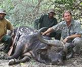 A buffalo hunter with his trackers and trophy.