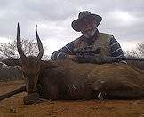 A hunter sits behind his bushbuck trophy.