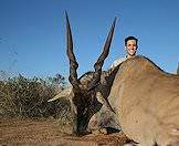 A hunter smiles happily next to his eland trophy.