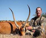 A hunter sits alongside his red lechwe trophy.