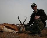 A hunter sits beside his springbok trophy.