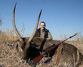 A hunter sits behind his waterbuck trophy for a photograph.