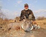 A proud bowhunter with his dog and his warthog trophy.