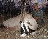 A bow hunter sits alongside his gemsbok trophy.